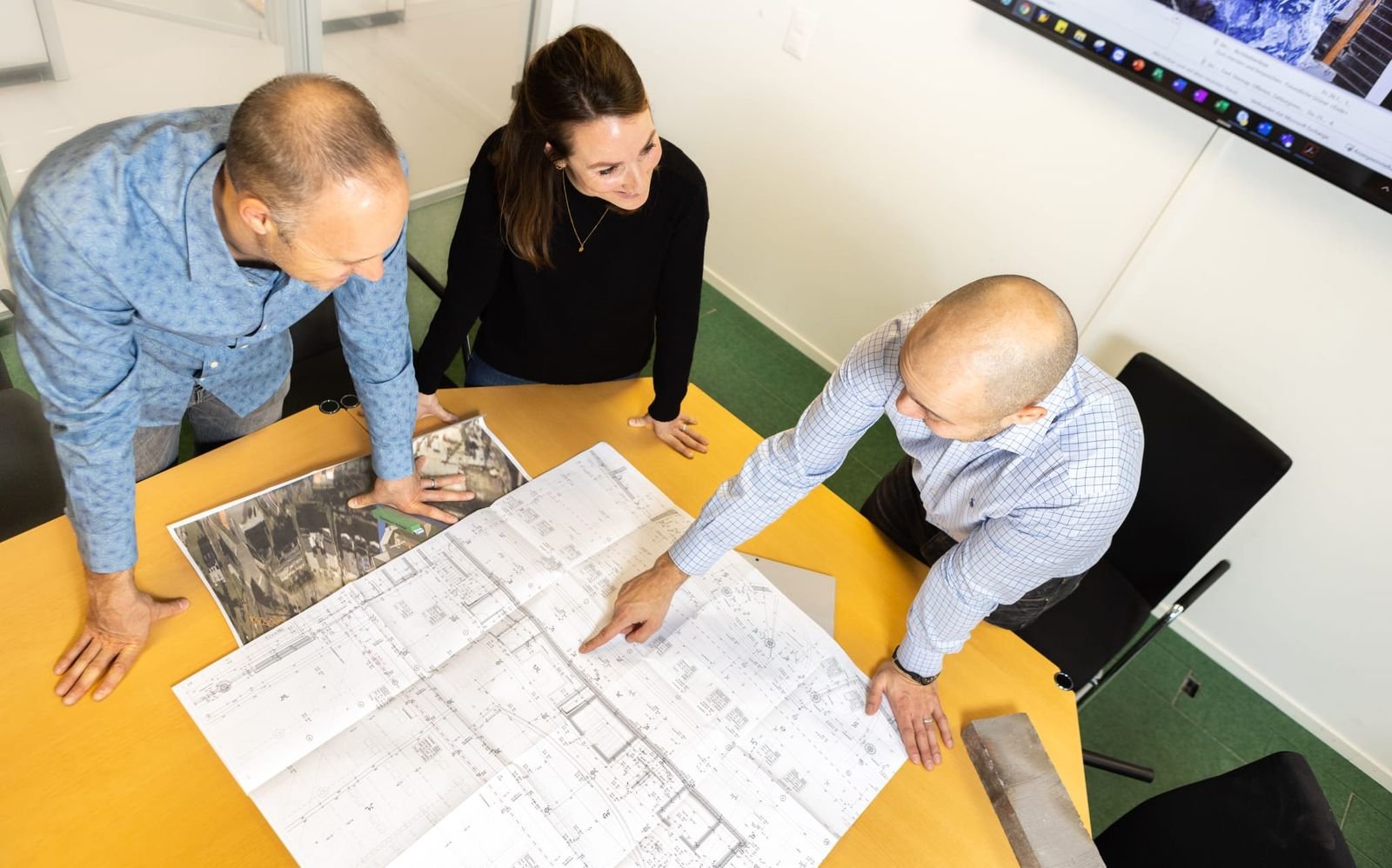 Planbesprechung am Tisch mit ausgebreiteten Bauplänen